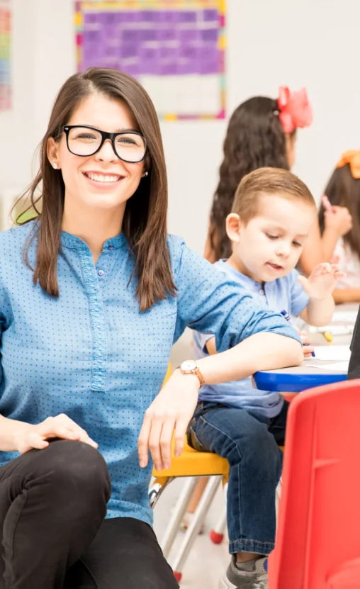 Teacher smiling with a child in a Creative Minds classroom